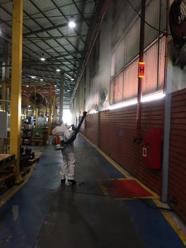 Técnico da AJM realizando atomização em galpão industrial