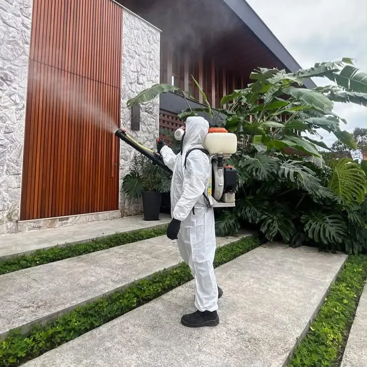 Técnico da AJM com atomizador costal aplicando produto em fachada